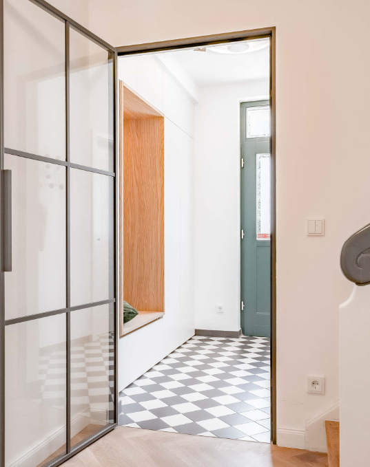 Heller Eingangsbereich von Haus K26 mit Stahltür und Schachbrettboden